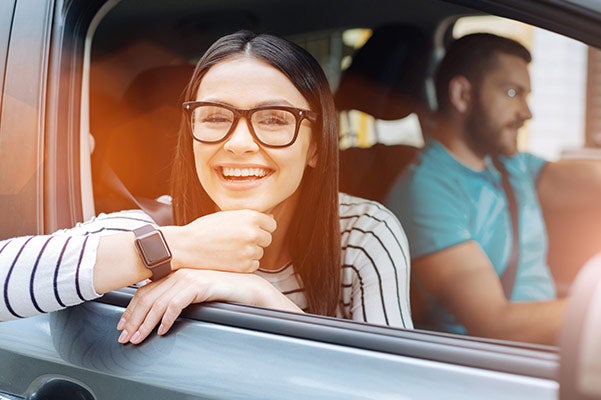 image of a woman hanging out of the passenger's side smiling with a man driving